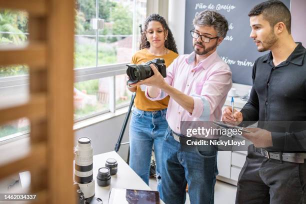 fotógrafo ensinando alunos sobre equipamentos de câmera em seu estúdio - studio photo - fotografias e filmes do acervo