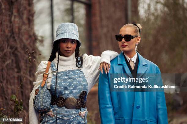 Petra Henriette Rufi wearing a white turtle neck top, blue denim overall with a white letter pattern, brown leather belt with metal buckle, light...