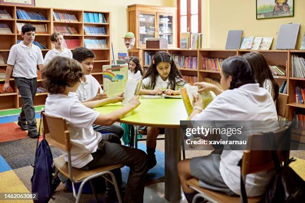 hispanic school children enjoying books in library - elementary school reading stock pictures, royalty-free photos & images
