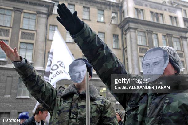 Activists from Oborona , a young group backed by the liberal Union of Right Forces and Yabloko salute wearing masks with the faces of Russian...