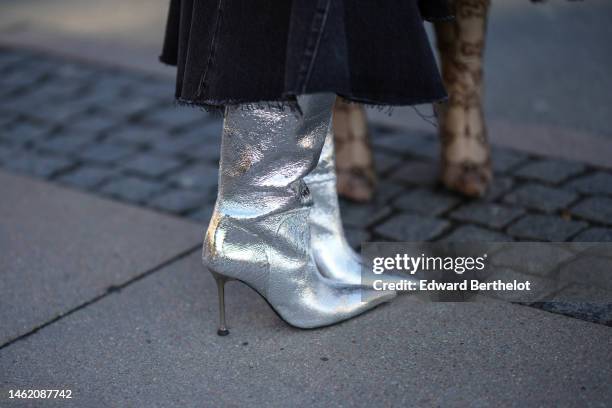 Marianne Theodorsen wears a black denim ripped asymmetric skirt, silver shiny leather pointed heels knees boots / high boots, outside Mark Kenly...