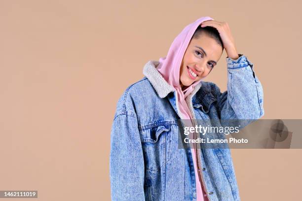 lateral view shot of a modern woman with big smile and shaved hair looking at the camera in a brown studio background - portraits studio smile stockfoto's en -beelden