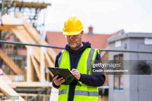 construction worker examining documents on clipboard - building construction site stock pictures, royalty-free photos & images