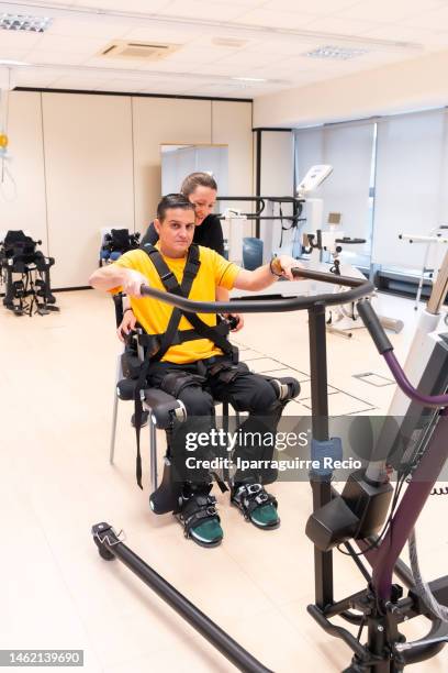 mechanical exoskeleton. physiotherapy in a modern hospital: physiotherapist positioning the disabled person to get up with the robotic skeleton. scientists, engineers and physiotherapy rehabilitation doctors use a tablet to help - esoscheletro di animale foto e immagini stock