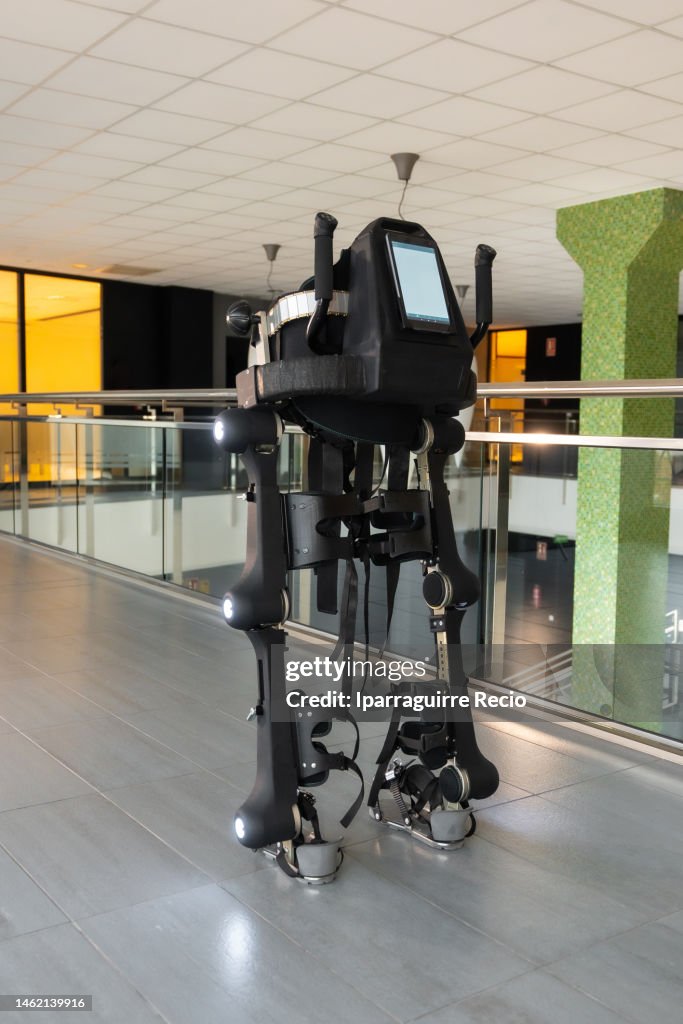 Mechanical exoskeleton. Physiotherapy in a modern hospital: Photo of the robotic skeleton turned on and with the lights illuminated. Scientists, engineers and physiotherapy rehabilitation doctors use a tablet to help