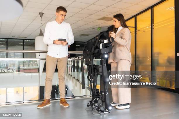 mechanical exoskeleton. physiotherapy in a modern hospital: physiotherapist and scientist preparing the robotic skeleton outside the rehabilitation box. scientists, engineers and physiotherapy rehabilitation doctors use a tablet to help - animal exoskeleton stock pictures, royalty-free photos & images