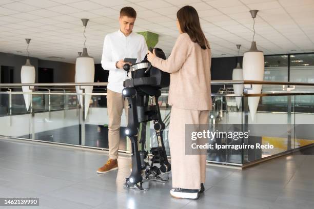 mechanical exoskeleton. physiotherapy in a modern hospital: physiotherapist and scientist looking at the functions on the tablet of the robotic skeleton outside the rehabilitation box. scientists, engineers and physiotherapy rehabilitation doctors use a t - esoscheletro di animale foto e immagini stock