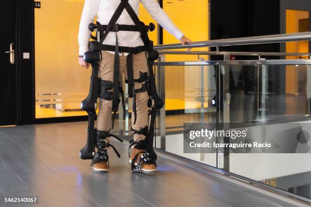 mechanical exoskeleton. physiotherapy in a modern hospital: patient walking with the robotic skeleton out of the rehabilitation box. scientists, engineers and physiotherapy rehabilitation doctors use a tablet to help - animal exoskeleton stock pictures, royalty-free photos & images