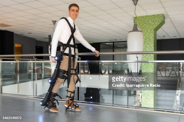 mechanical exoskeleton. physiotherapy in a modern hospital: patient walking and smiling with the robotic skeleton outside the rehabilitation box. scientists, engineers and physiotherapy rehabilitation doctors use a tablet to help - exoskeleton stock pictures, royalty-free photos & images