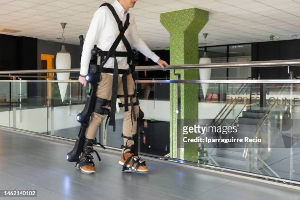 mechanical exoskeleton. physiotherapy in a modern hospital: patient walking for the first time with the robotic skeleton outside the rehabilitation box. scientists, engineers and physiotherapy rehabilitation doctors use a tablet to help - animal exoskeleton stock pictures, royalty-free photos & images