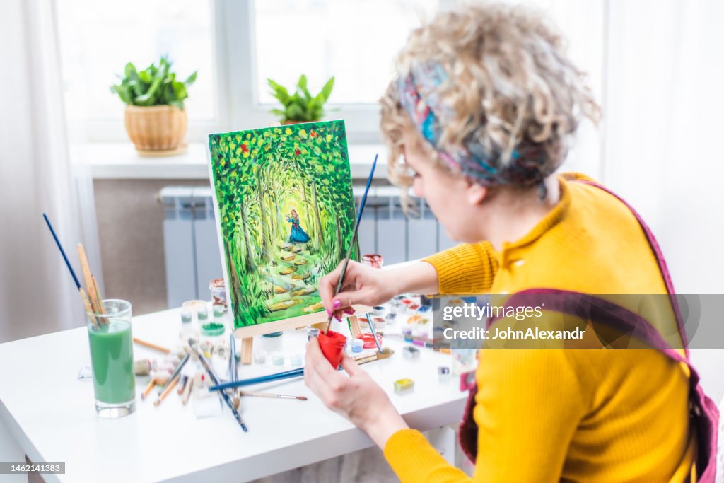 Curly blonde woman painting a picture by the window