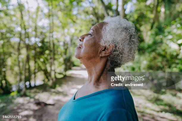 retrato de una mujer mayor respirando aire fresco - respirar fotografías e imágenes de stock