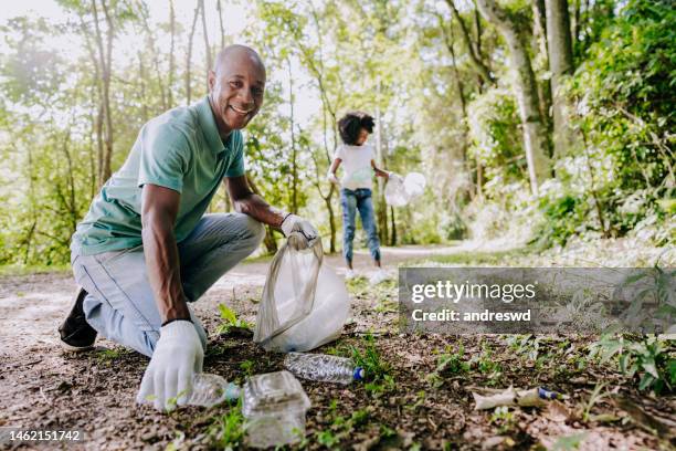 mature man picking up trash in nature - black man picking up trash stock pictures, royalty-free photos & images
