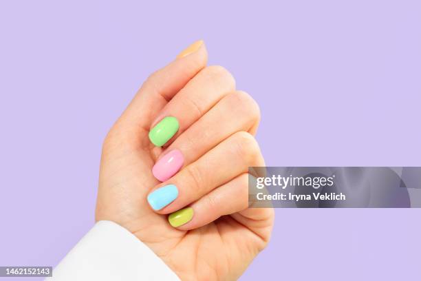 elegant woman's hand with pastel color manicure on easter holiday. trendy color of the year 2022 very peri purple violet lavender color background. woman dressed in fashionable white shirt. - manicured hands stock pictures, royalty-free photos & images