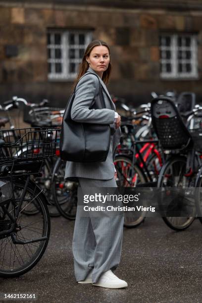 Mathilde Ravn wears grey blazer and pants suit, black bag Copenhagen Studios, white sneakers Copenhagen Studios on February 01, 2023 in Copenhagen,...