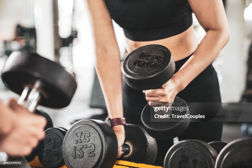 Athletic woman doing exercise for arms. Photo of muscular fitness model working out with dumbbells. Strength and motivation. Woman doing lunges exercise with dumbbells in gym.