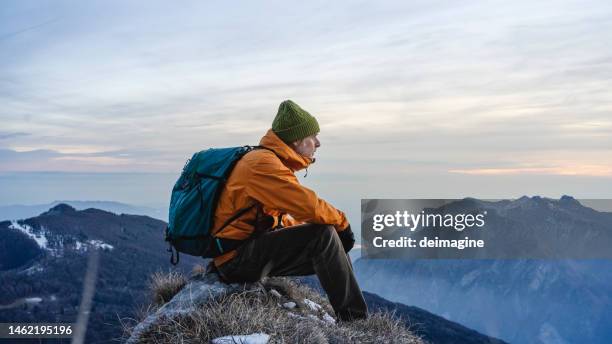 wanderer sitzen blick auf die landschaft auf dem gipfel des berges - poträt mann frühling stock-fotos und bilder