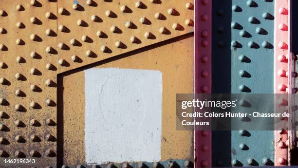 riveted, painted and weathered metal plates in brown, blue and pink in london - sheet metal stock pictures, royalty-free photos & images