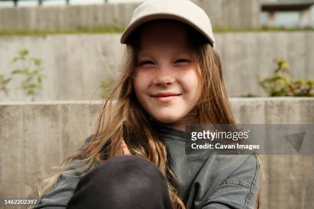 portrait of smiling girl in cap at street - 12 13 jahre mädchen stock-fotos und bilder