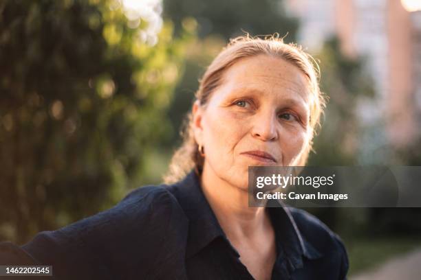 portrait of thoughtful mature business woman looking away in park - pension ukraine stock pictures, royalty-free photos & images