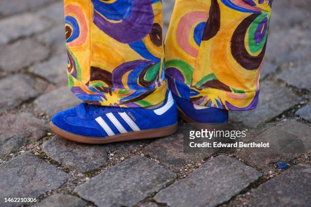 Guest wears yellow with brown / blue / green print pattern large pants, royal blue suede sneakers from Adidas , outside Helmstedt, during the...