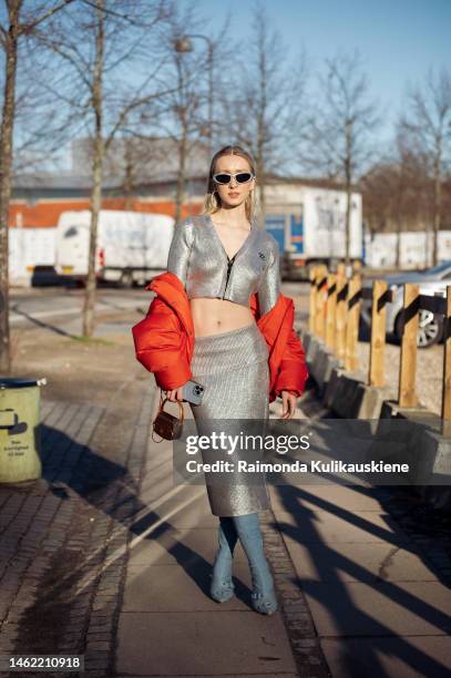 Guest wearing sunglasses with silver frame, silver hoop earrings, a silver metallic long sleeves cropped top, a matching long silver skirt from...