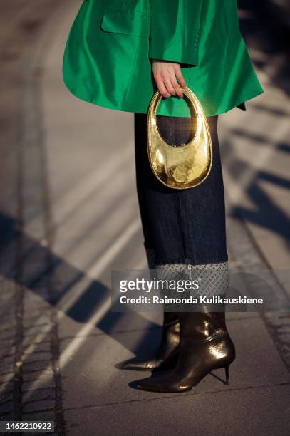 Guest wearing cropped dark jeans, green shirt, green blazer, black sunglasses, and golden bag outside Munthe during the Copenhagen Fashion Week...