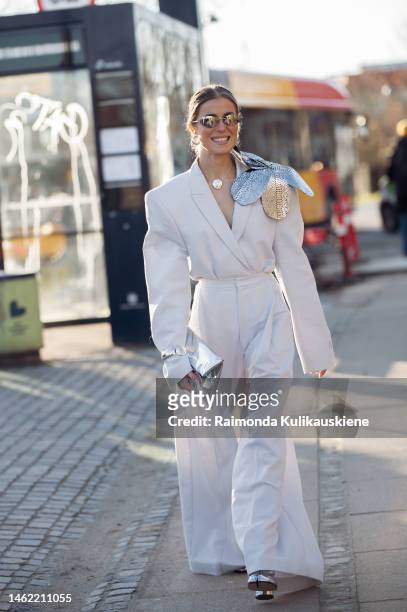 Nina Sandbech wearing white wide pants, blazer with big silver flower on the shoulder, silver bag and silver shoes outside Munthe during the...