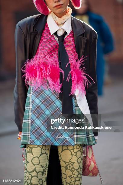 Guest wearing pink ear warmers, black leather jacket, white shirt, pink shiny leather west with fur, blue, green, brown checkered skirt, and olive...