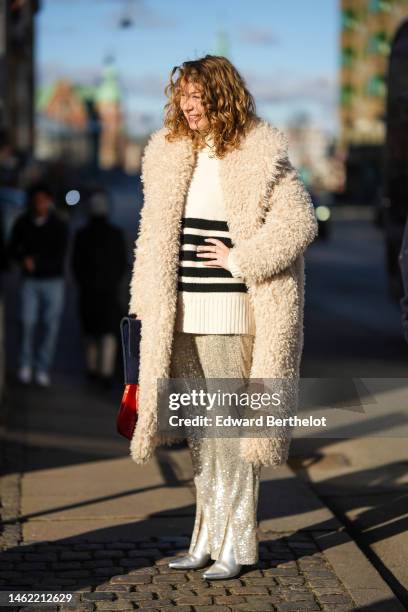 Guest wears a white wool with black striped print pattern oversized pullover, a white latte oversized long fluffy coat, silver sequined large pants,...