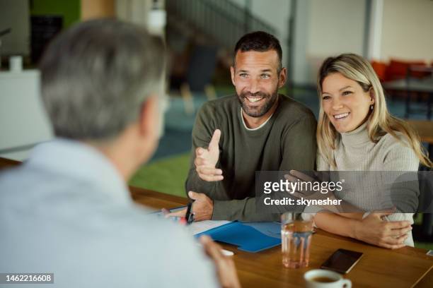 glückliches paar im gespräch mit ihrem versicherungsvertreter bei einem treffen im büro. - financing stock-fotos und bilder