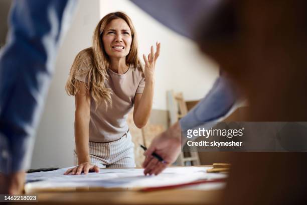 frustrated woman talking to real estate agent in the apartment. - woede stockfoto's en -beelden