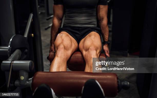 muscular man doing legs in the gym - quadriceps stockfoto's en -beelden