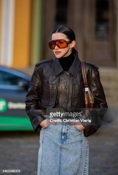 Guest wears brown leather jacket, denim skirt, sunglasses outside Gestuz during the Copenhagen Fashion Week Autumn/Winter 2023 on February 02, 2023...