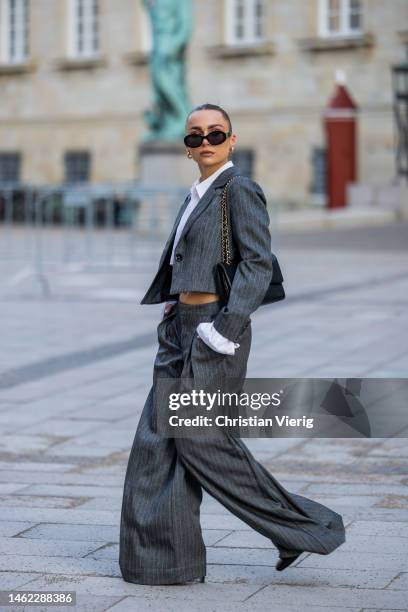 Anna Idriess wears grey cropped blazer, wide let pants, cropped white blouse black Chanel bag outside Gestuz during the Copenhagen Fashion Week...