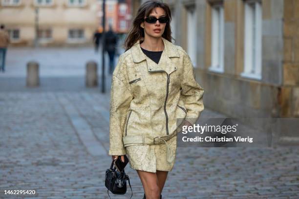 Mara Lafontan wears beige leather jacket, skirt, black knee high boots, black bag outside Gestuz during the Copenhagen Fashion Week Autumn/Winter...