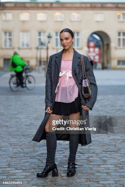 Model Clemence Bertrand wears grey coat, Chanel bag, rose see trough top, black skirt, knee high socks outside Gestuz during the Copenhagen Fashion...