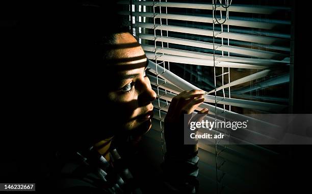 woman looking out window - woman peeking through blinds stock pictures, royalty-free photos & images