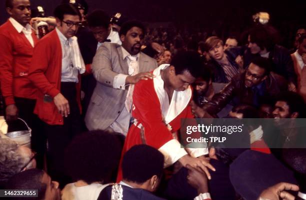 Trainer Angelo Dundee , American businessman Jabir Herbert Muhammad and American heavyweight boxing champion Muhammad Ali walk out of the ring after...