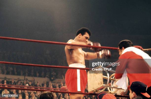 American heavyweight boxing champion Muhammad Ali waits to sit down as his trainer Angelo Dundee puts down the stool during the 'Fight of the...