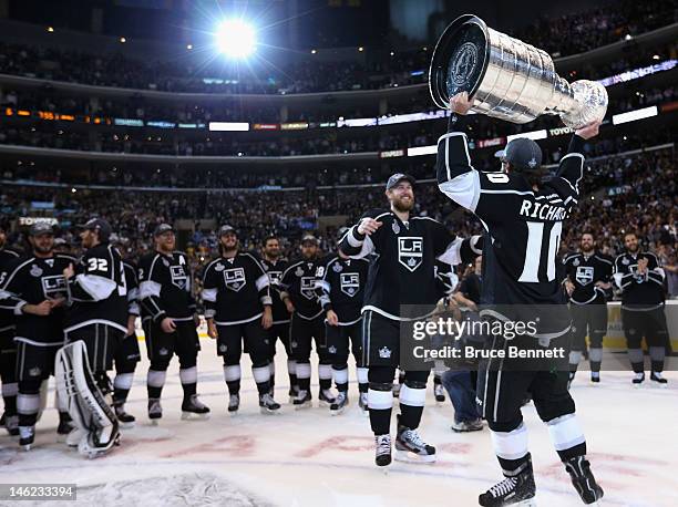 Mike Richards of the Los Angeles Kings hands the Stanley Cup off to Jeff Carter after the Kings defeated the New Jersey Devils 6-1 to win the Stanley...