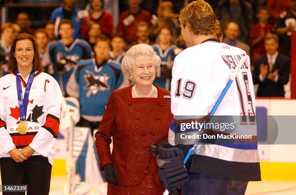 Cassie Campbell watches as Vancouver Canucks captain Markus Naslund hands Queen Elizabeth the hockey puck after the drop at centre ice at General...