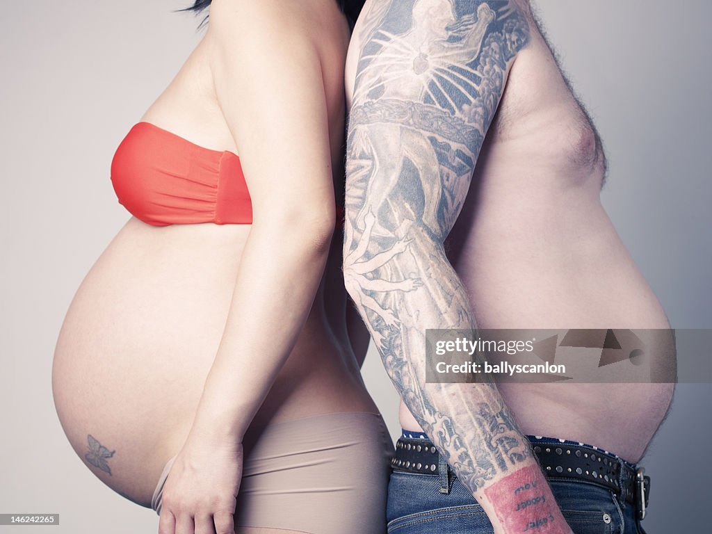 Pregnant couple with man imitating pregnancy