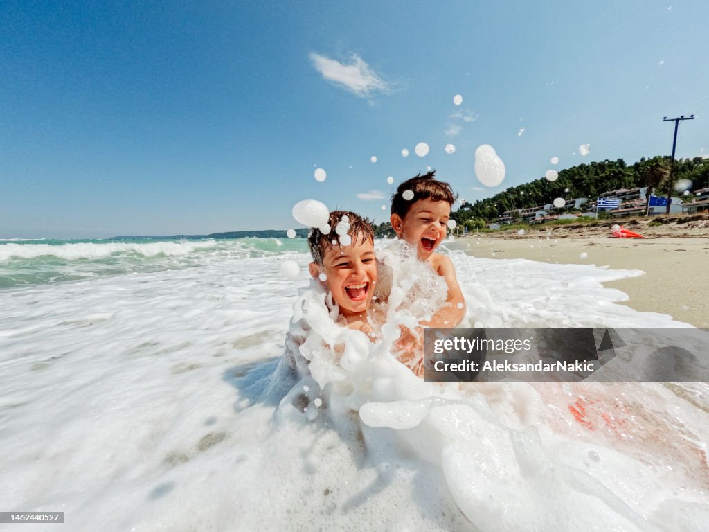 Junge Jungen, die mit Wellen spielen