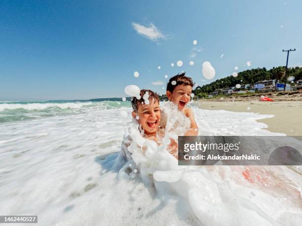 junge jungen, die mit wellen spielen - family beach holiday stock-fotos und bilder