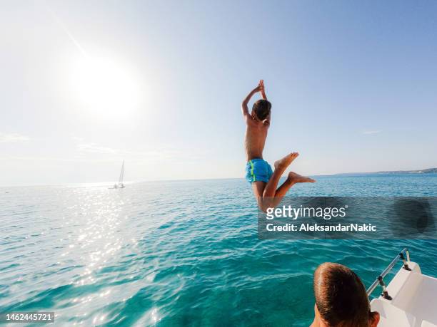 garçon sautant dans la mer depuis le pédalo - jumping of boat photos et images de collection