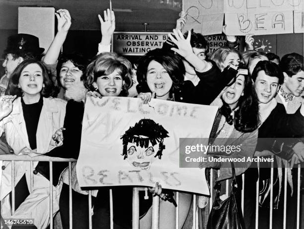 Screaming teenagers wave a crude sign as they welcome 'The Beatles' to John F. Kennedy Airport, New York, New York, February 7, 1964.