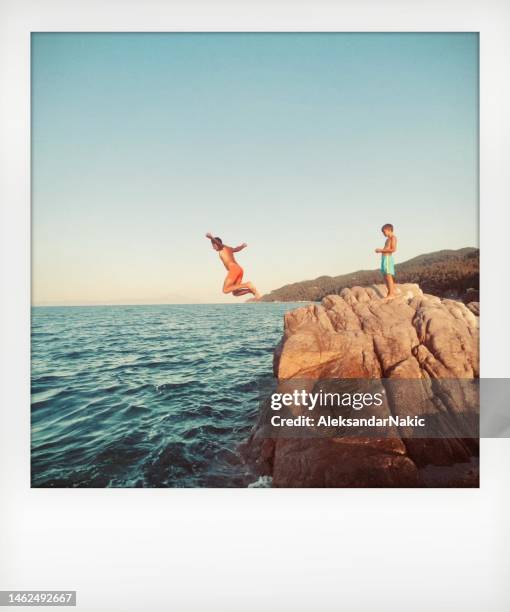 père et fils sautant dans la mer - transfert de photo instantanée photos et images de collection