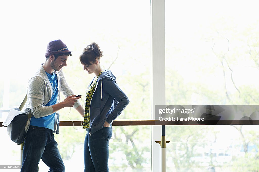 Young adults sharing music from mobile phone