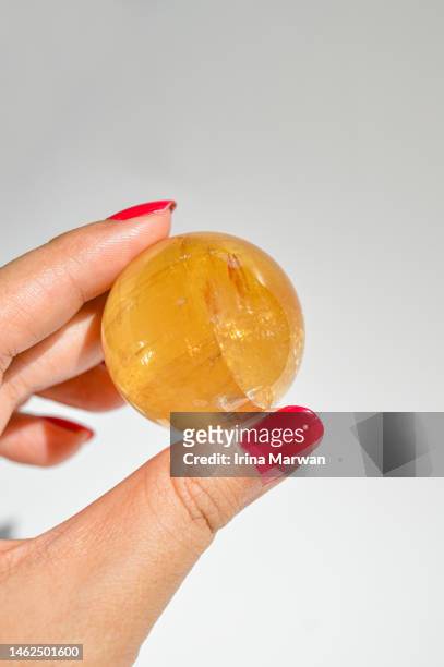 woman holding honey calcite crystal sphere - calcita fotografías e imágenes de stock